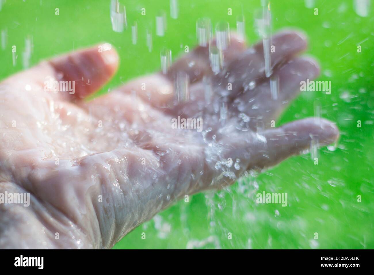 Water splashing on an outstretched hand. Stock Photo