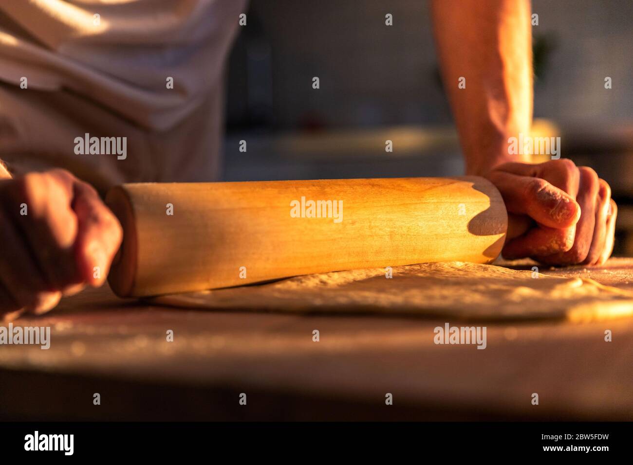 Man hands roll out the dough with a rolling pin on the kitchen table, selective soft focus. Concept of cooking dough, pizza, baking, recipes. Stock Photo