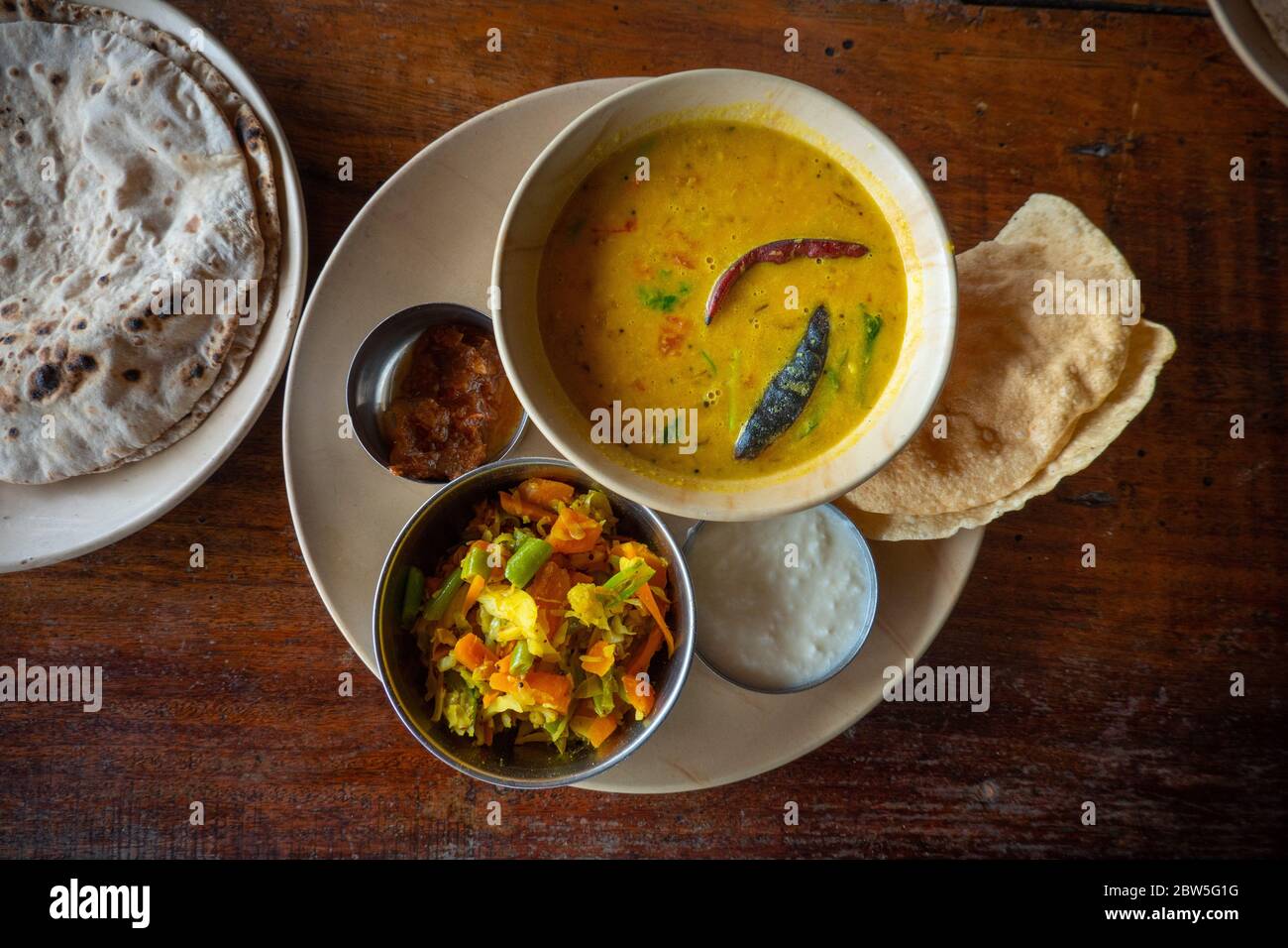 A yellow curry served with popadoms, vegetable salad and chapati at a restaurant in Mahabalipuram, India Stock Photo