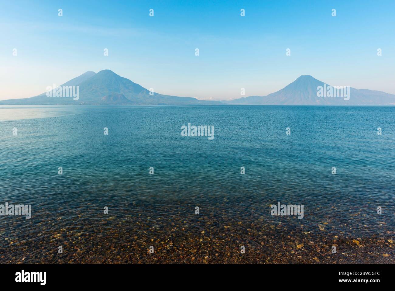 The Atitlan, Toliman and San Pedro Volcano at sunrise by the shore of the Atitlan Lake, Panajachel, Guatemala. Stock Photo