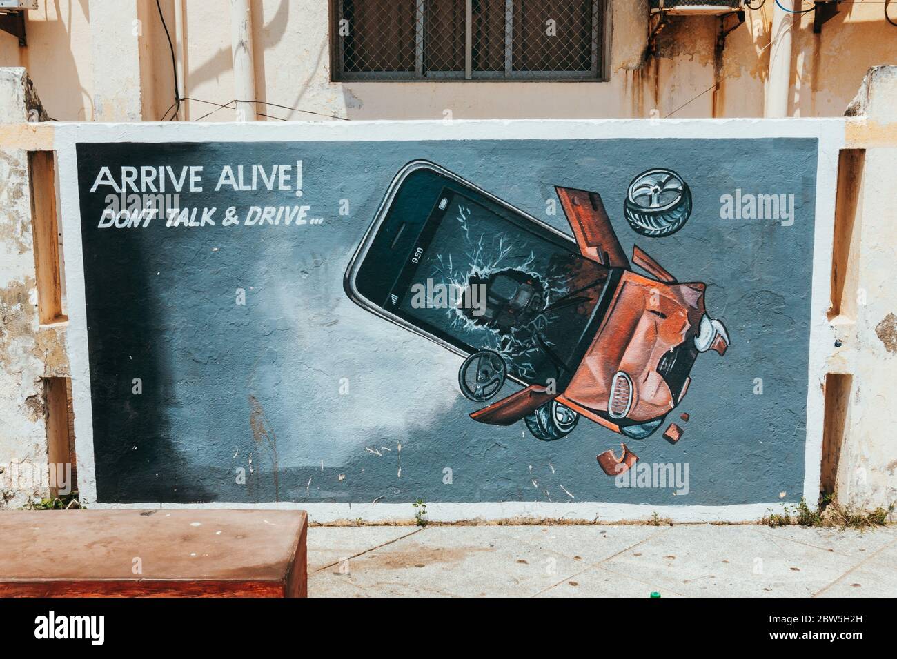 'Arrive alive! Don't talk & drive' - a hand-painted safe driving advertisement in Pondicherry, India, depicting a mobile phone smashed into a vehicle Stock Photo