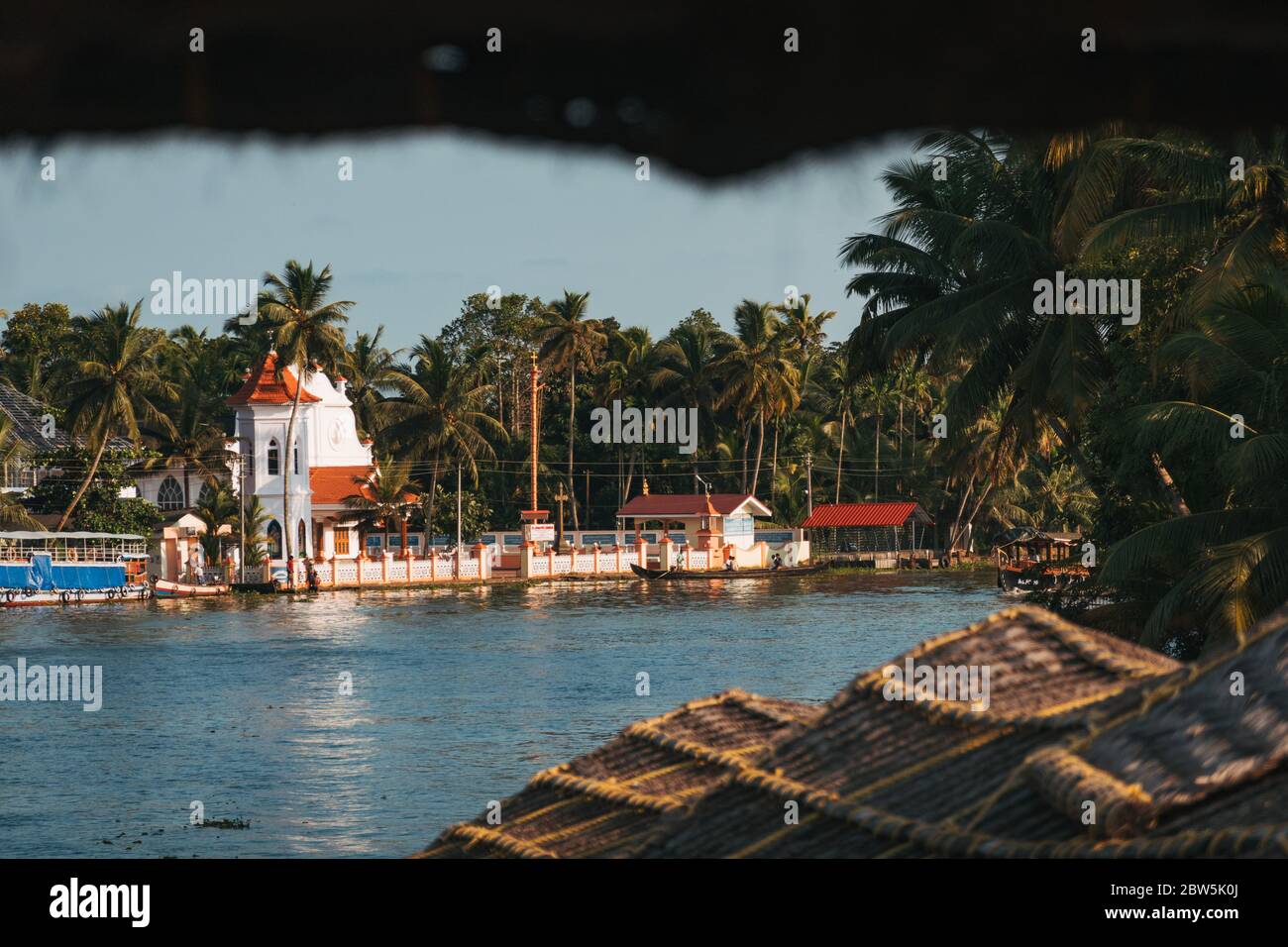 A small Christian church on the banks of the Kerala backwaters in India, seen from the rear of a houseboat Stock Photo