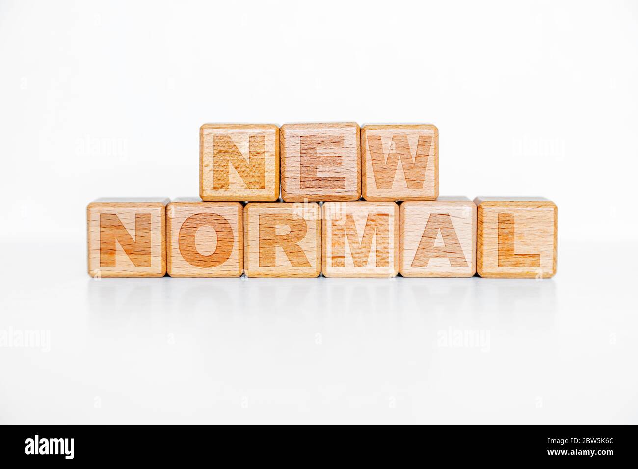 NEW NORMAL word on engraved wooden alphabet cube blocks. Concept of new normal lifestyle after COVID-19 coronavirus pandemic with physicall distancing Stock Photo