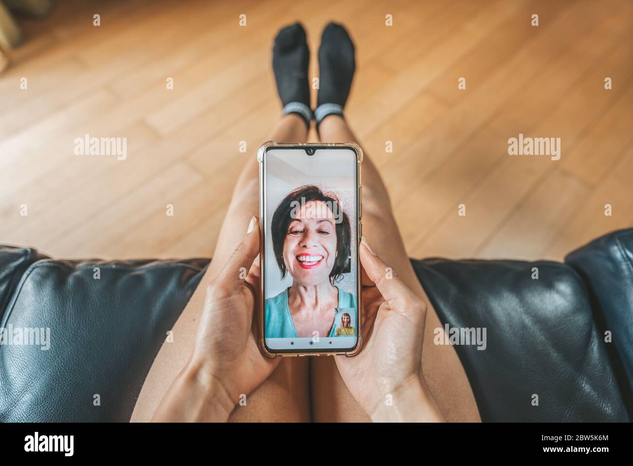 Daughter talking with mother online using smartphone on video call. Close up on phone screen, focus on hands. Quarantine mood. Stock Photo