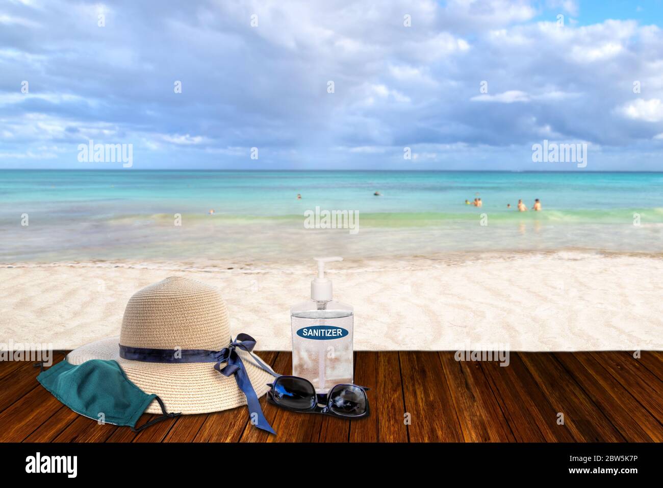 Vacationing in the New Normal after COVID-19 coronavirus pandemic. Tourism concept showing sandy beach with beach straw hat, sunglasses, hand sanitize Stock Photo