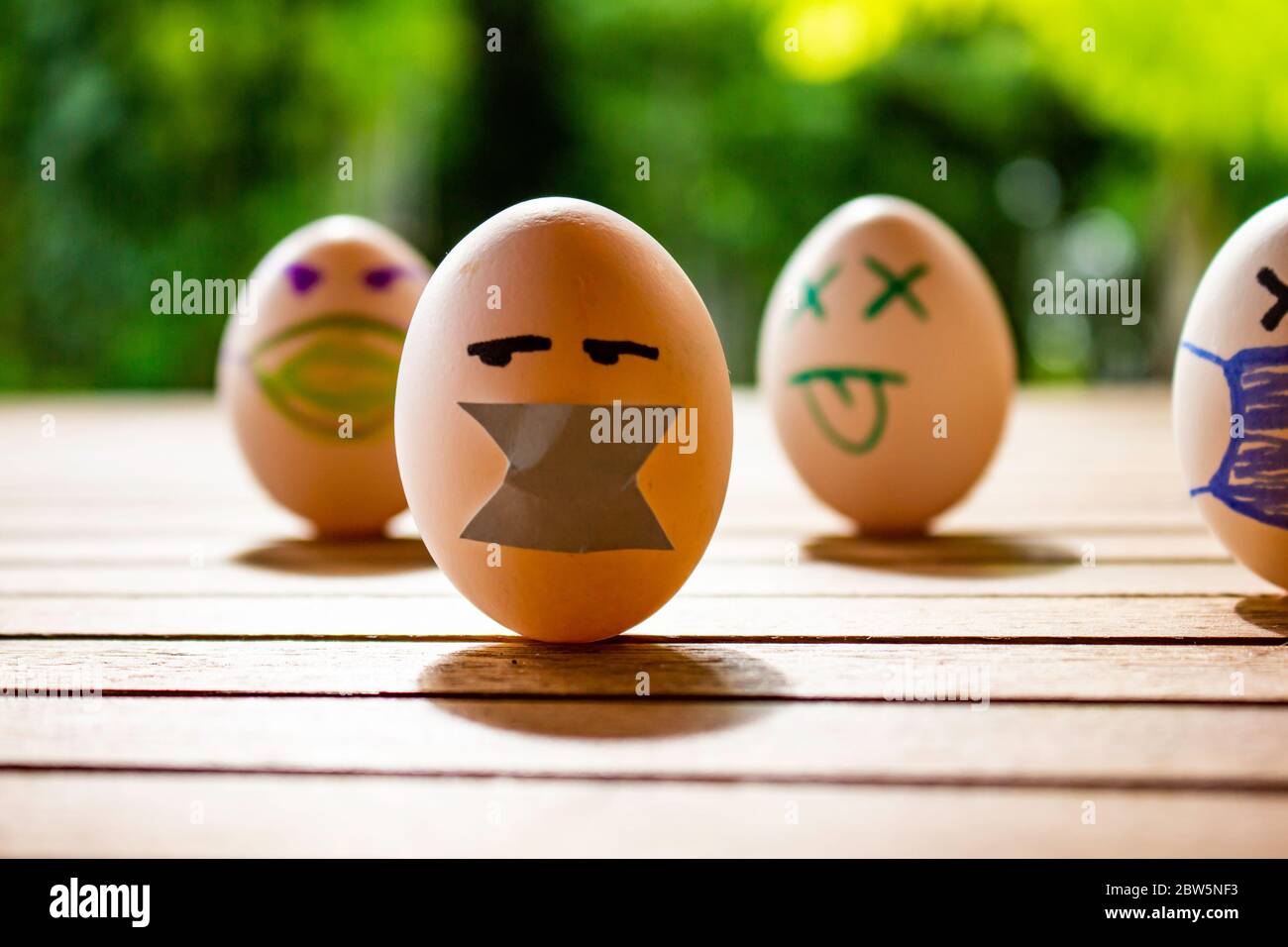 Eggs with drawings of faces with chinstraps. Concept of protection and social distancing. Eggs on a table. Contagious disease concept. Stock Photo