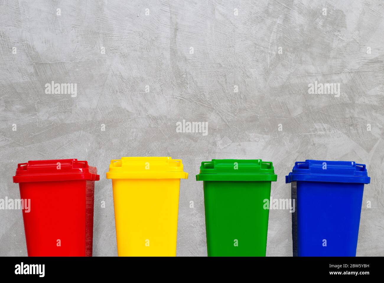 Red, Yellow, Green and Blue Recycle Bins. Concrete wall background ...