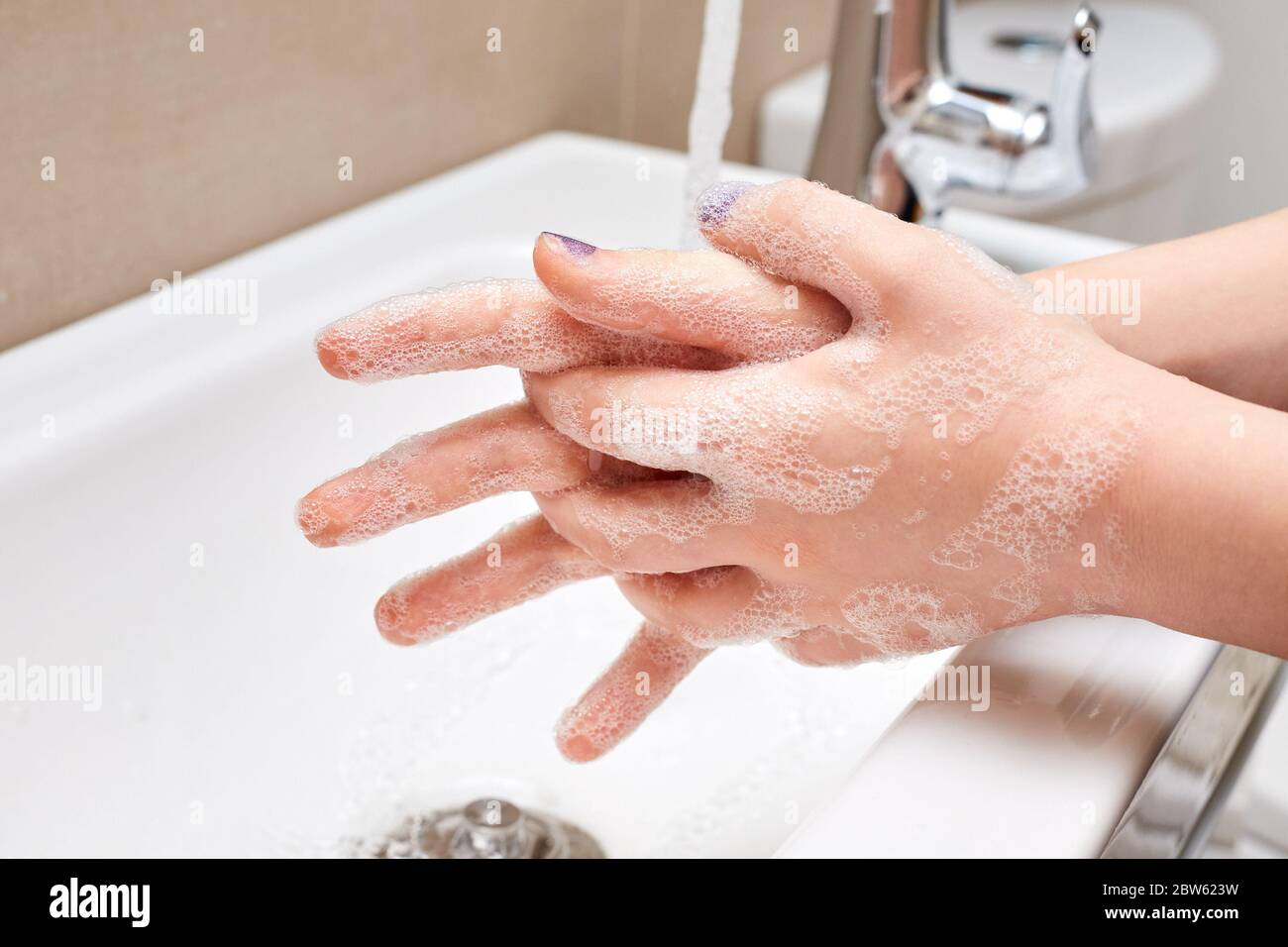White Child Washing Hands with Soap and Running Water over Sink, Fingers Extended Stock Photo