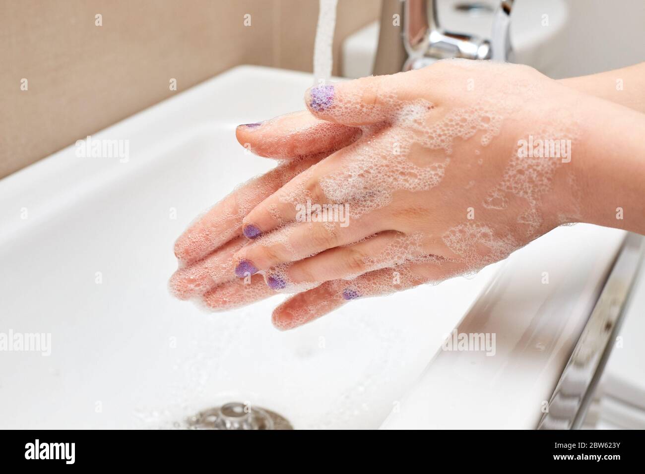 White Child Washing Hands with Soap and Running Water over Sink, Fingers Together Stock Photo