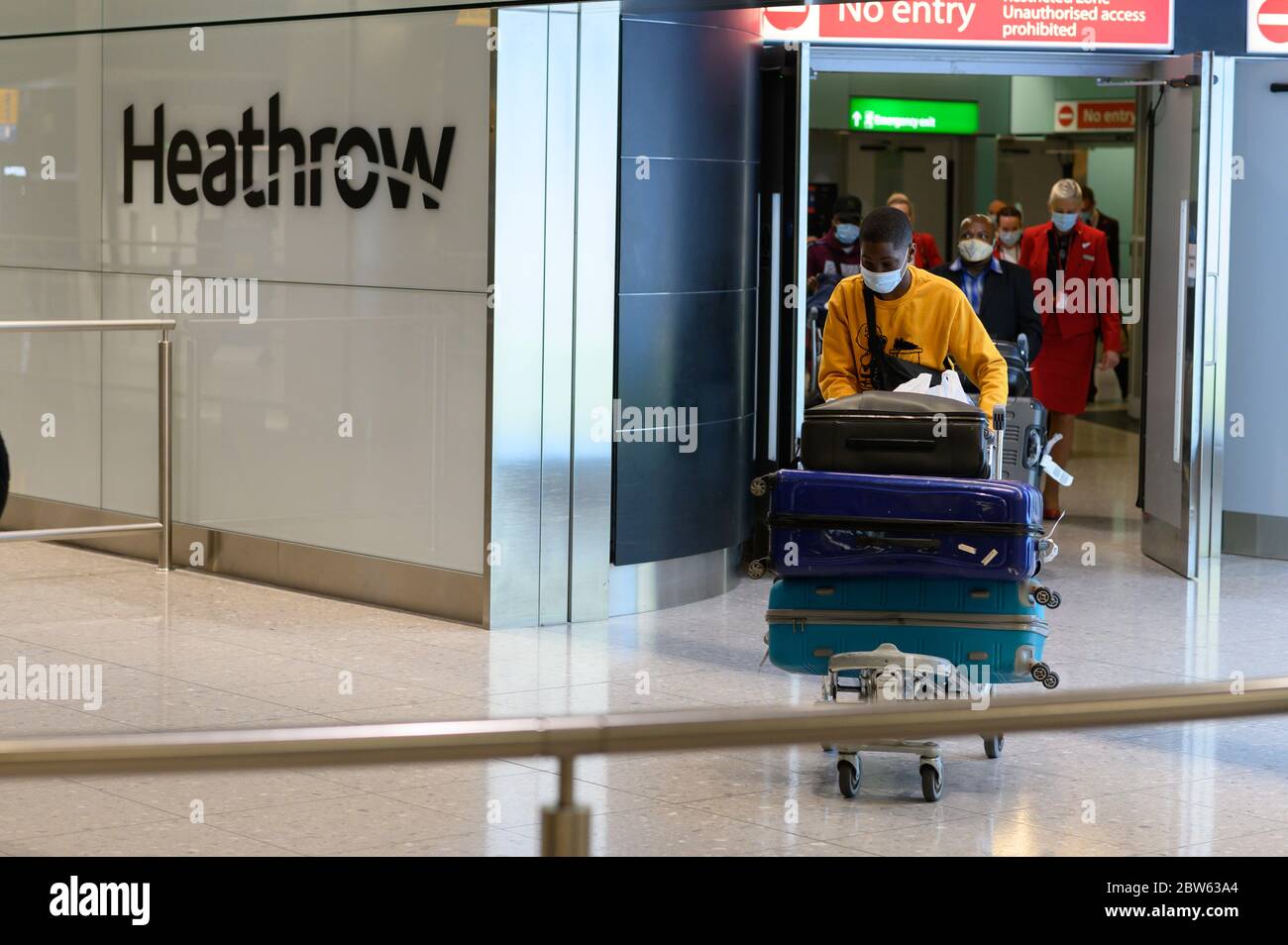 British man pushing luggage, arrives at Heathrow terminal 2 from Lagos, Nigeria Stock Photo