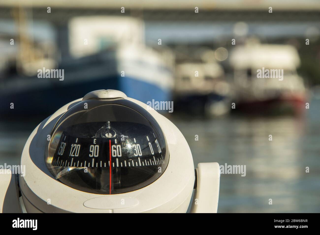 Close-up of a compass on a boat passing by the anchored ships Stock Photo