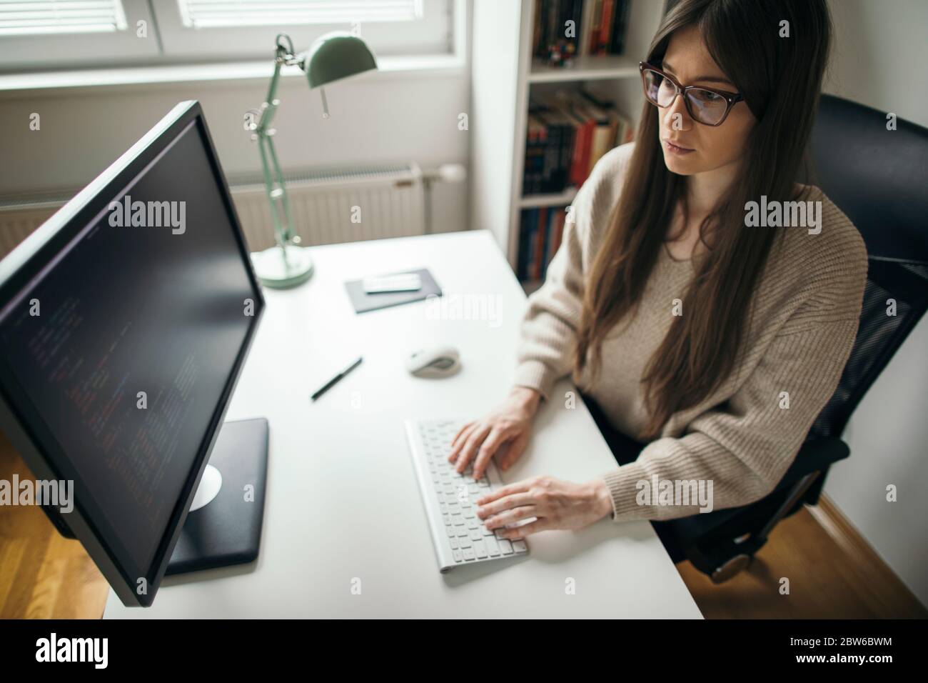 Young woman programming at her home office. Female programmer ponting ...