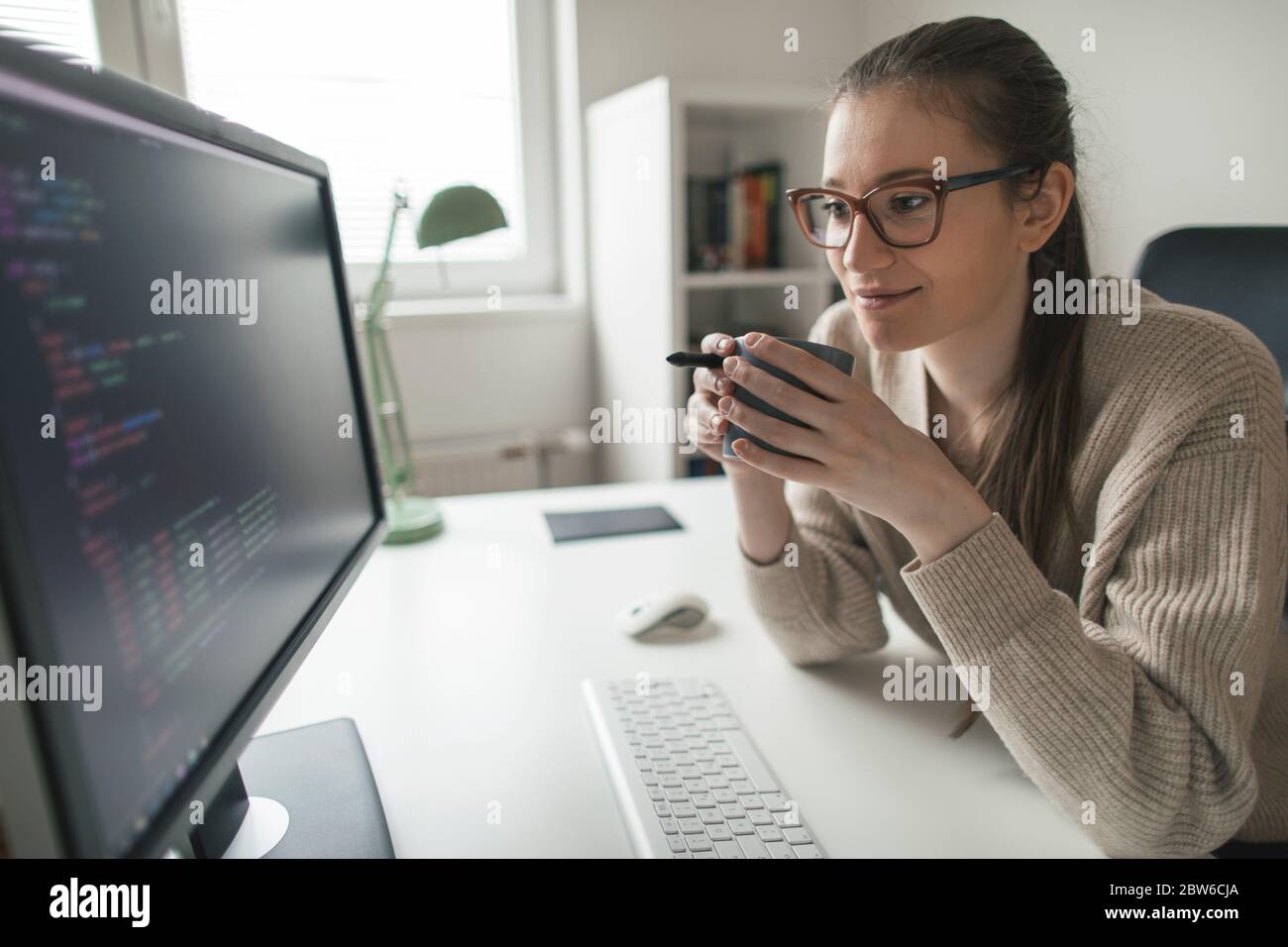 Young woman programming at her home office. Female programmer ponting ...