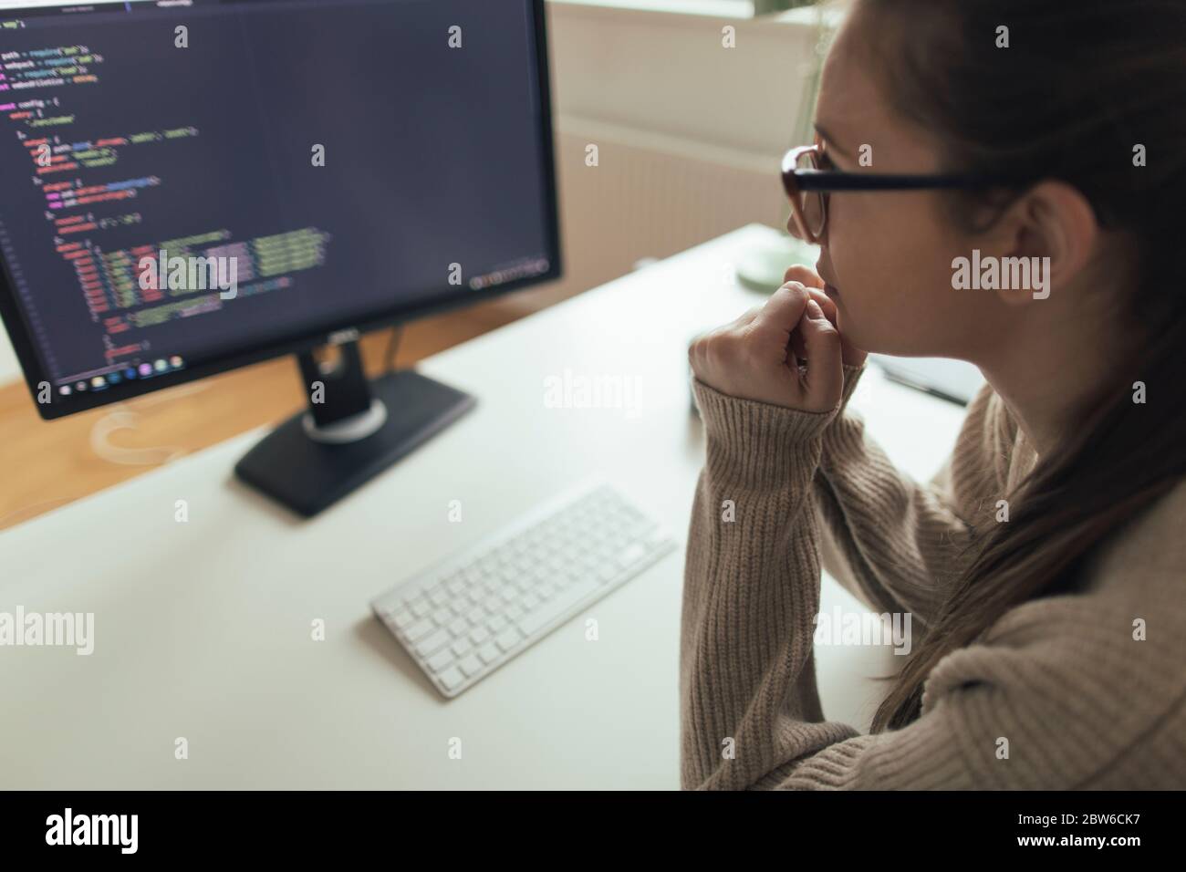 Young woman programming at her home office. Female programmer ponting ...