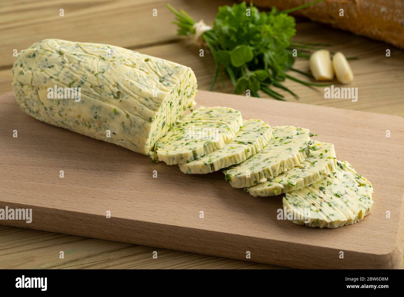 Sliced fresh made herb butter close up on a cutting board Stock Photo