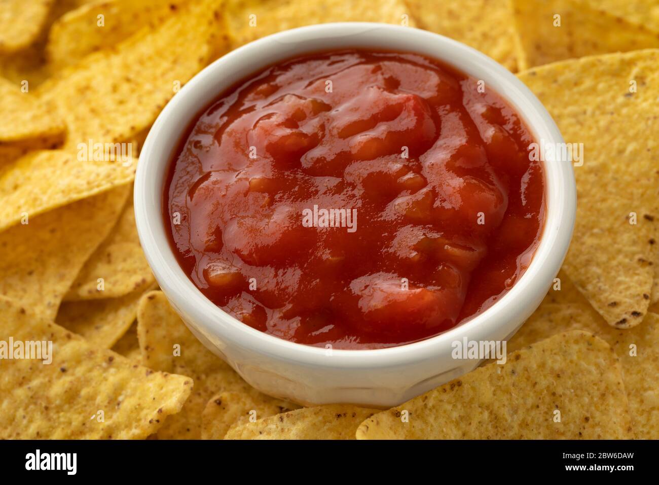 Bowl of red spicy mexican salsa surrounded by tortilla chips Stock Photo