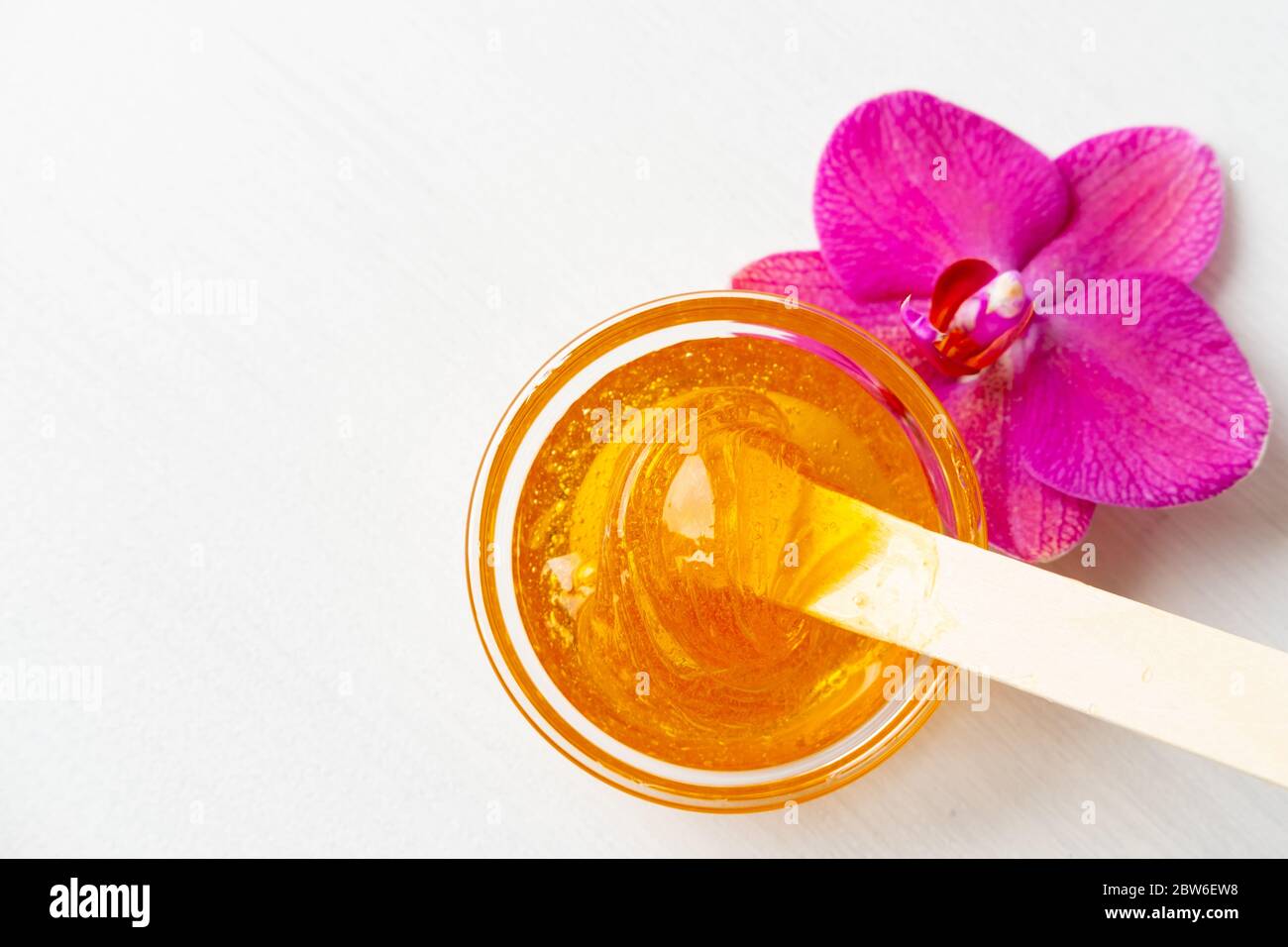 sugar paste or wax honey for hair removing with wooden waxing spatula sticks. flower background - depilation and beauty concept Stock Photo