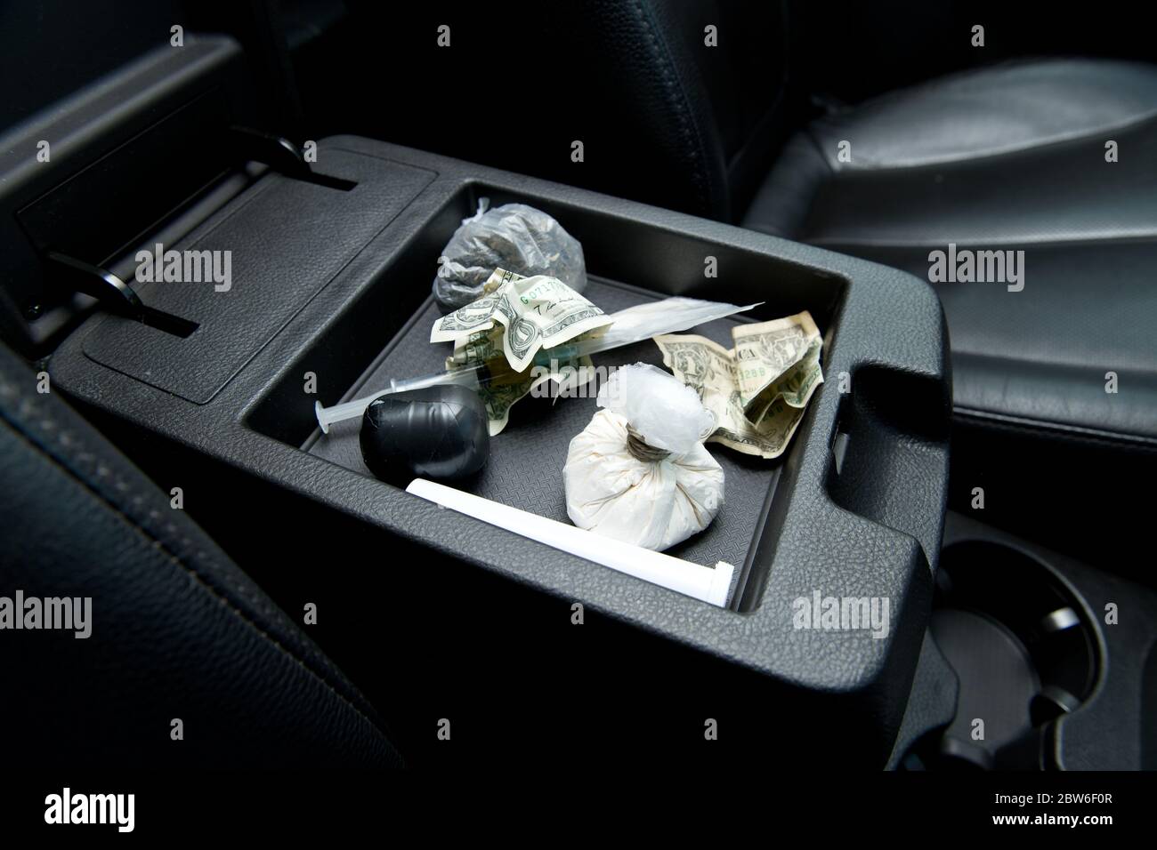 crumpled dollars and various drugs for testing are in the armrest of the drug dealer s car Stock Photo