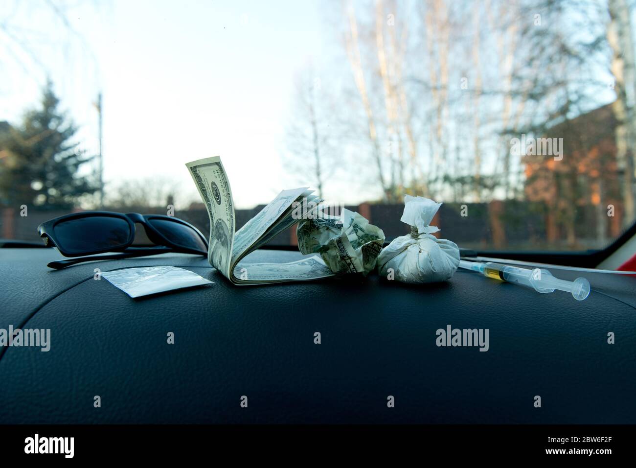 Drugs and dollars are on the dashboard of a drug dealer car Stock Photo