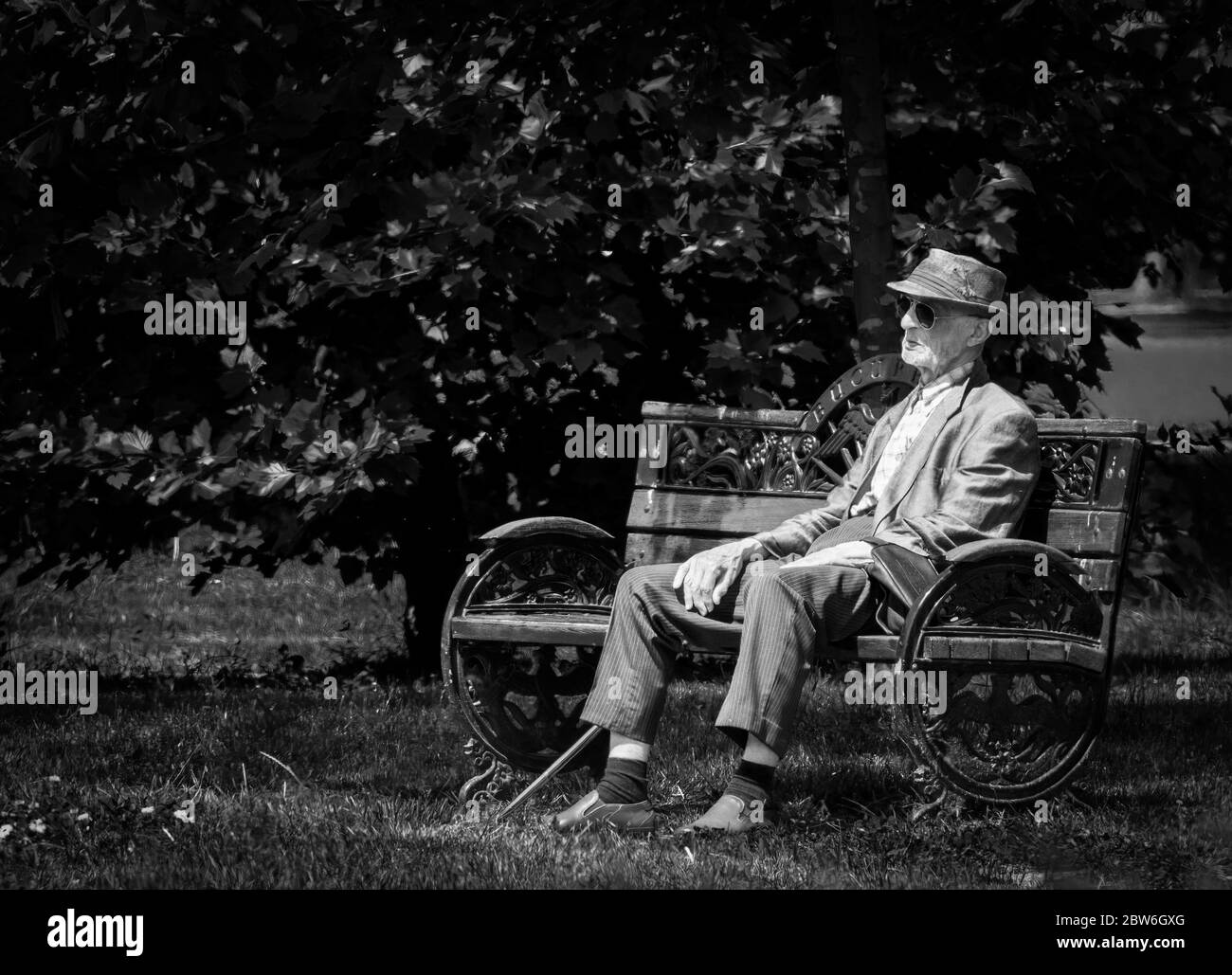 Bucharest/Romania - 05.21.2020: Lonely old man sitting on a bench in the Herestrau Park, Bucharest. Senior resting on a bench. Stock Photo