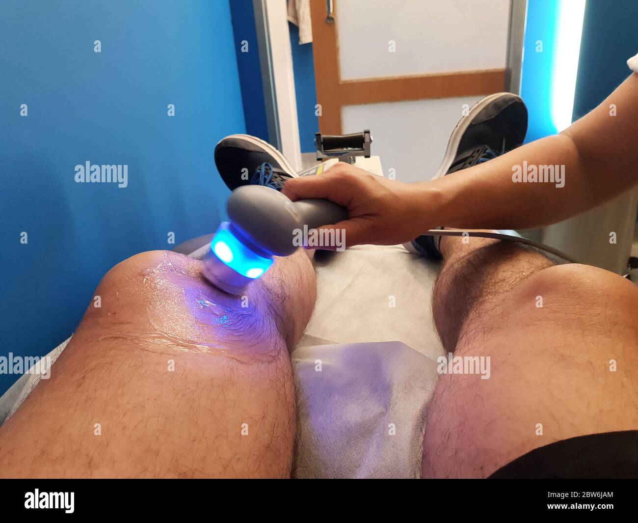 Physiotherapist is applying ultrasound therapy on the knee injury with ultrasound head transducer, blured motion Stock Photo