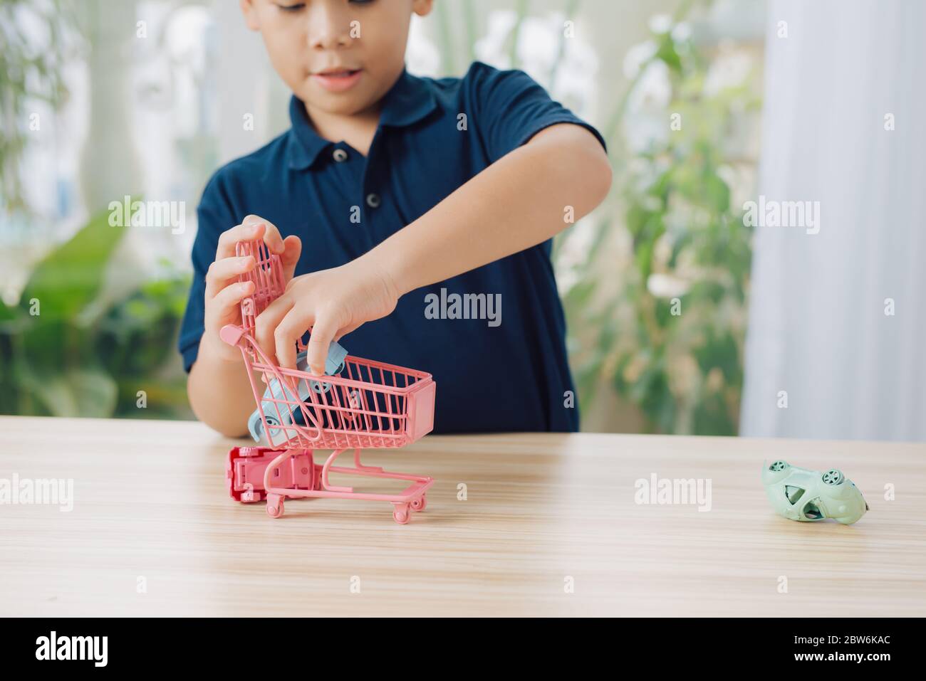 boy playing toy cars on table Stock Photo