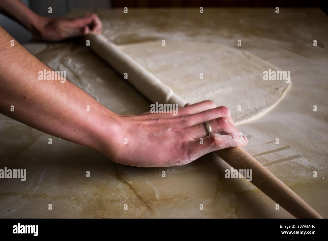 Woman hands using rolling pin in the kitchen to make dough Stock Photo