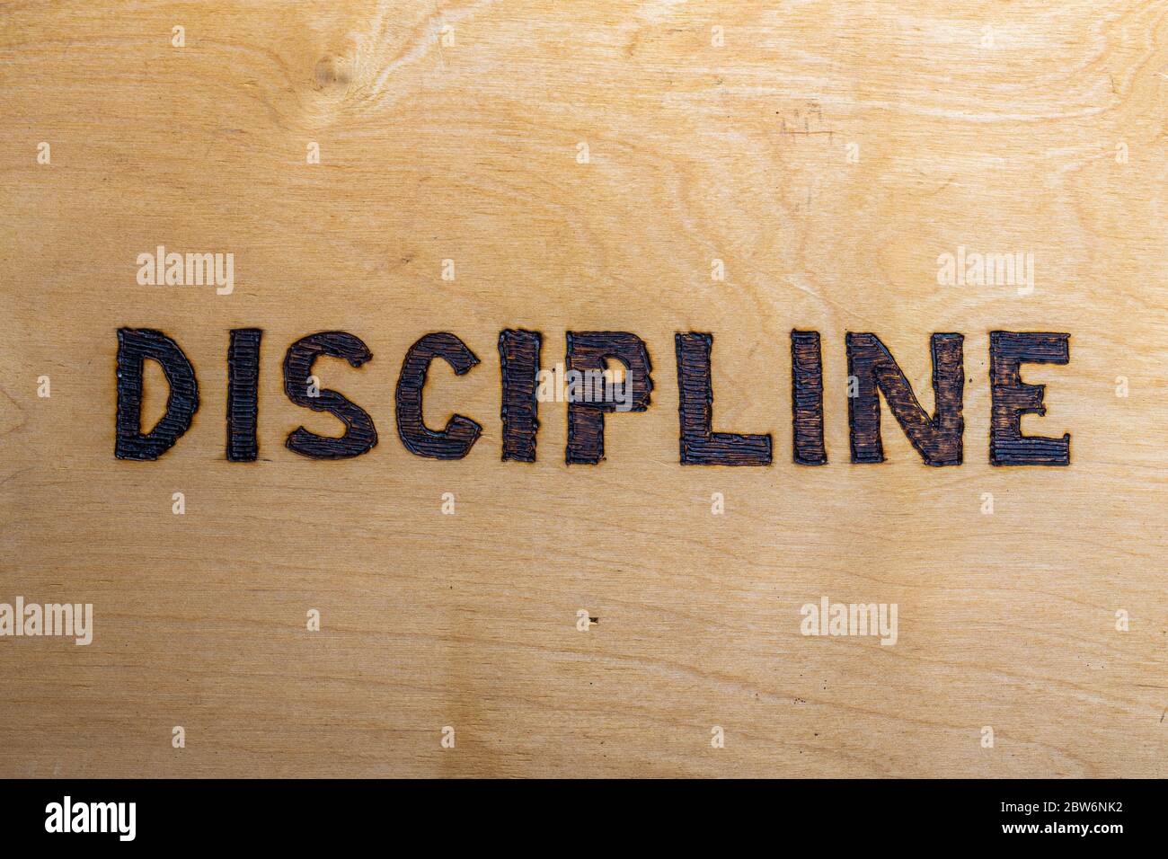 the word discipline burnt on white flat wooden surface - directly above normal view Stock Photo