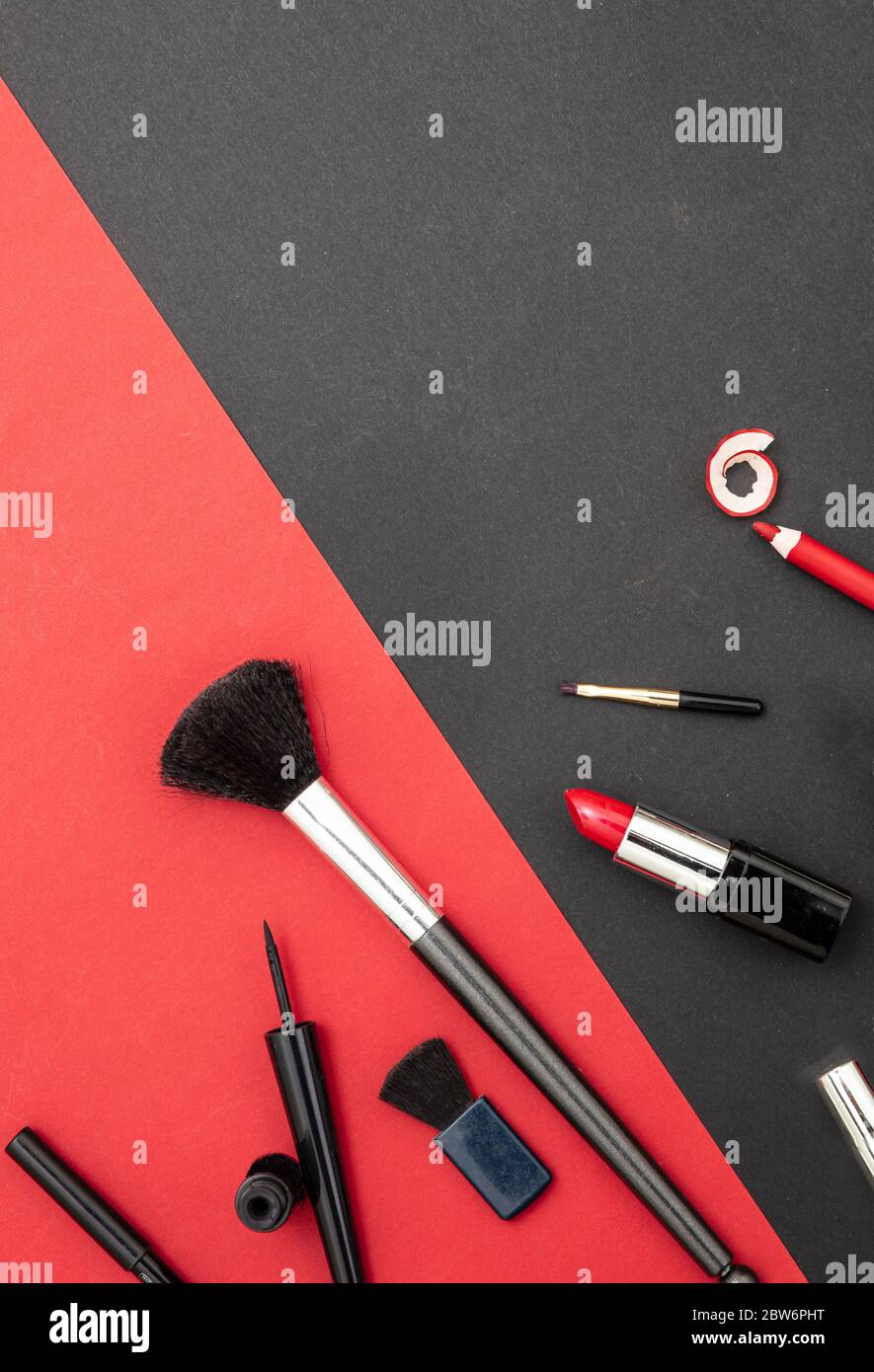 Make up cosmetics accessories in red and black. Lipstick, nail polish, eye pencil and brushes against red and black color background Stock Photo