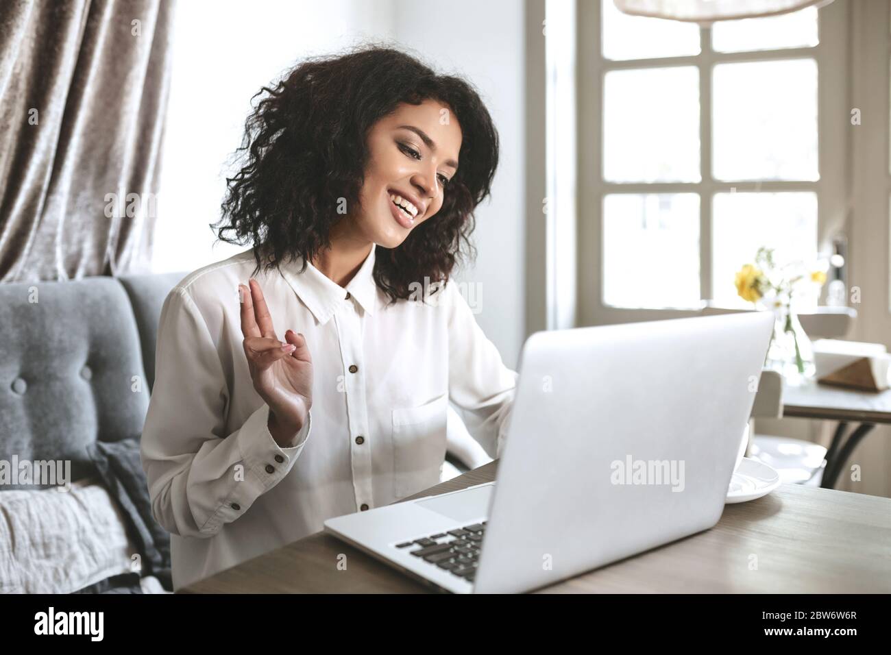 Pretty African American girl sitting in restaurant with laptop. Young ...