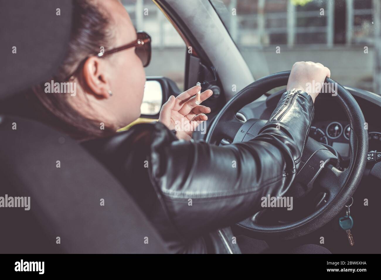 Close up of woman hand smoking cigarette inside the car while driving a