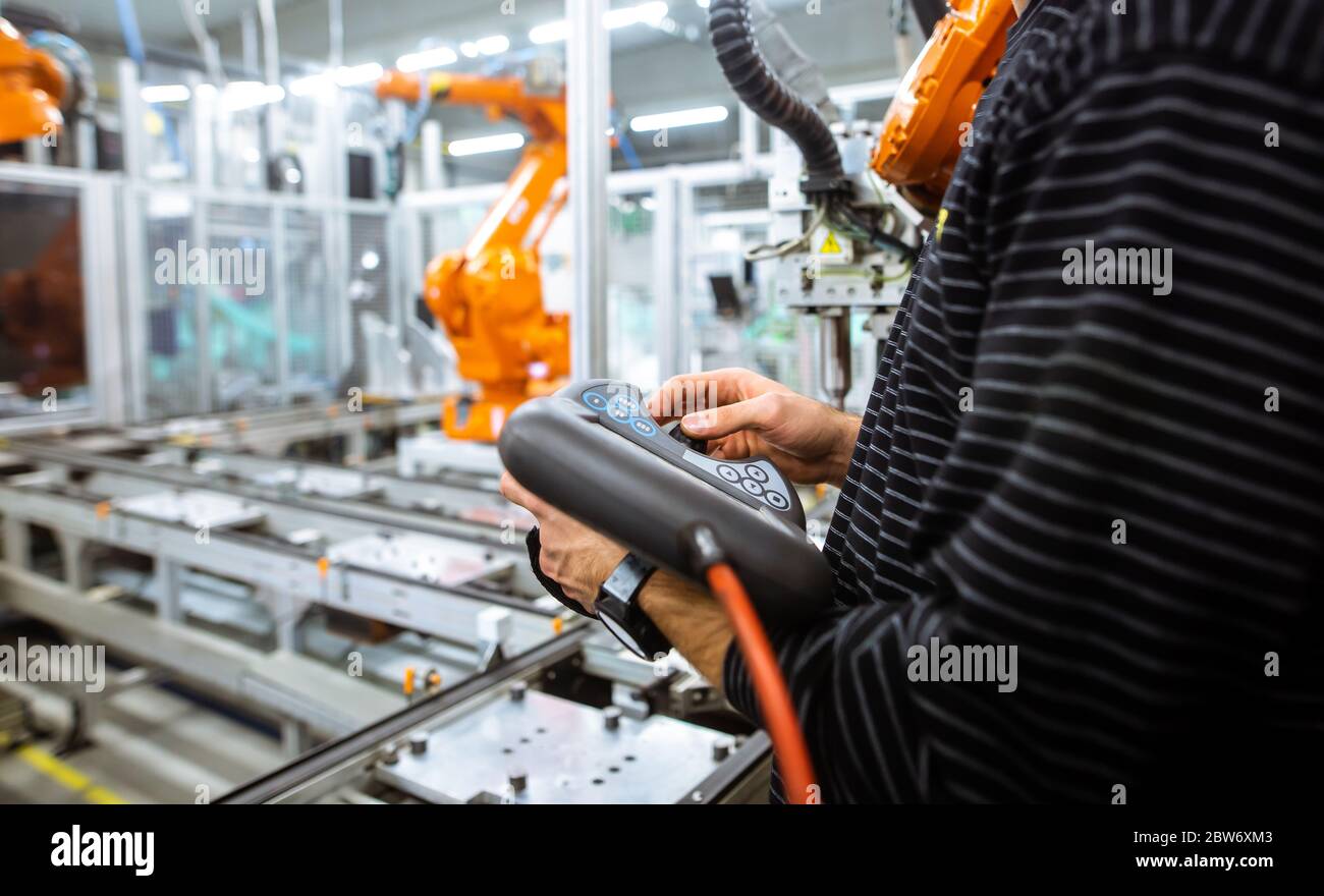 Engineer setting up automatic robot arms in the smart factory, automotive industry, industrial concept Stock Photo