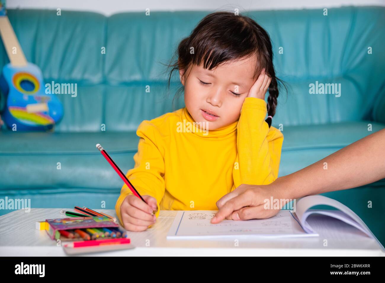 School Home work concept, Asian little girl children wearing yellow casual clothing and confused face, headache when mother taught learning school Stock Photo