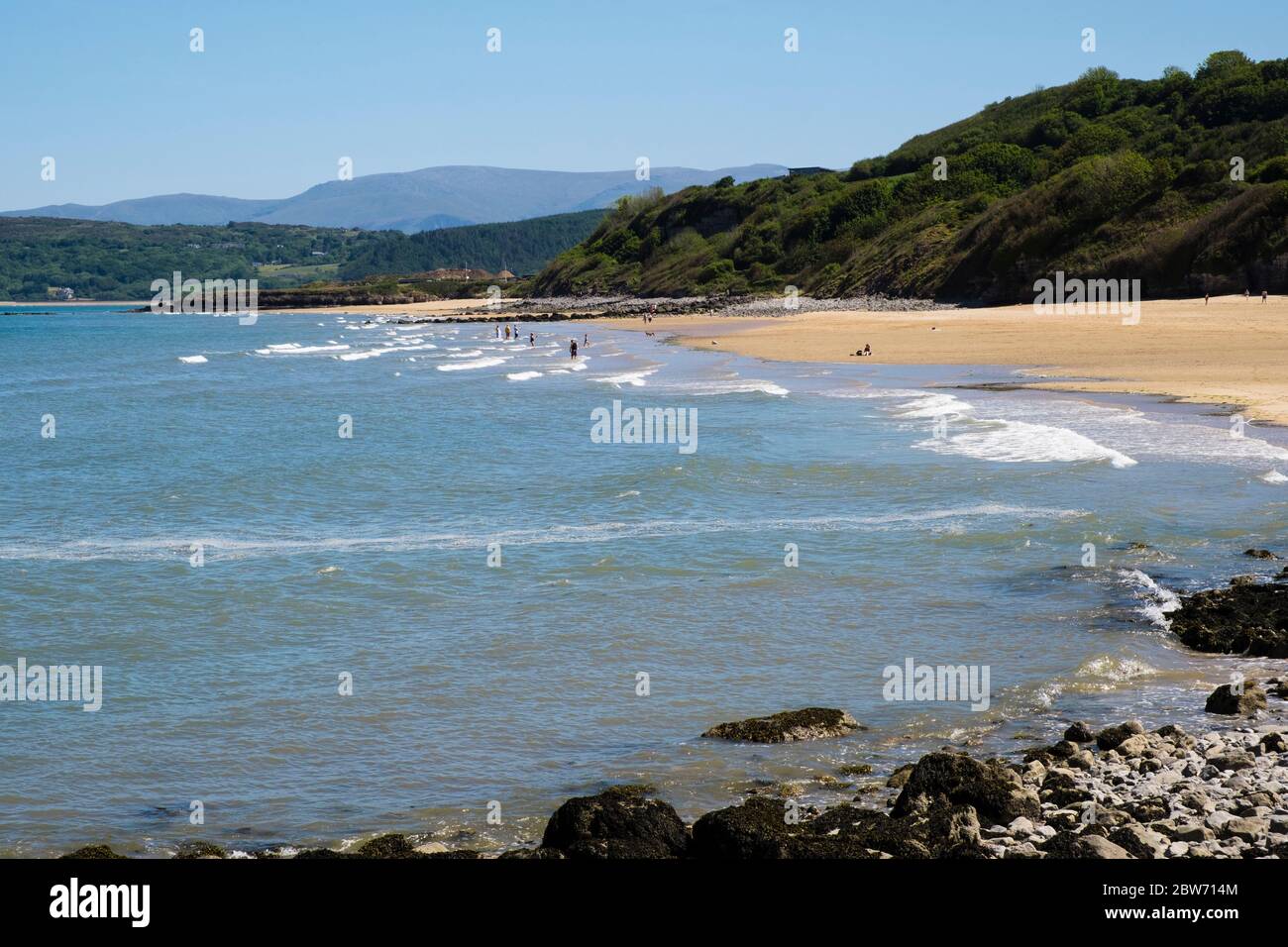 A few people social distancing in sea on quiet beach during COVID-19 pandemic lockdown at half term holiday. Benllech Anglesey Wales UK Britain Stock Photo