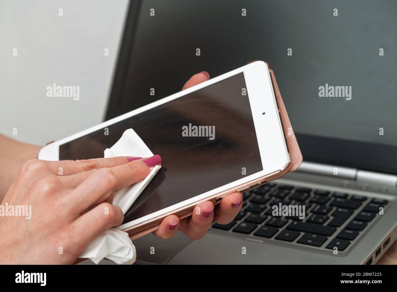 Woman cleaning tablet device with cotton paper tissue, wiping black