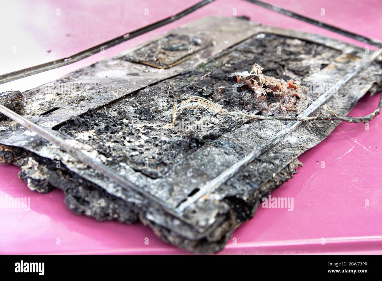 Broken laptop computer spoiled by flame of hot fire. Destroyed notebook, melted plastic. Computer damage, data destruction concepts. Stock Photo