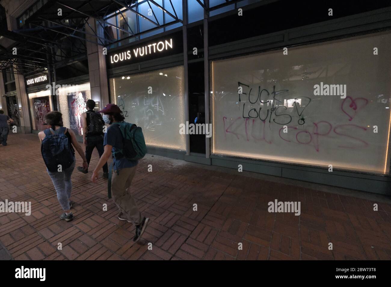 Portland, USA. 29th May, 2020. Protesters walk by graffiti on the Louis  Vuitton store in Portland, Ore., on May 29, 2020. (Photo by Alex Milan  Tracy/Sipa USA) Credit: Sipa USA/Alamy Live News