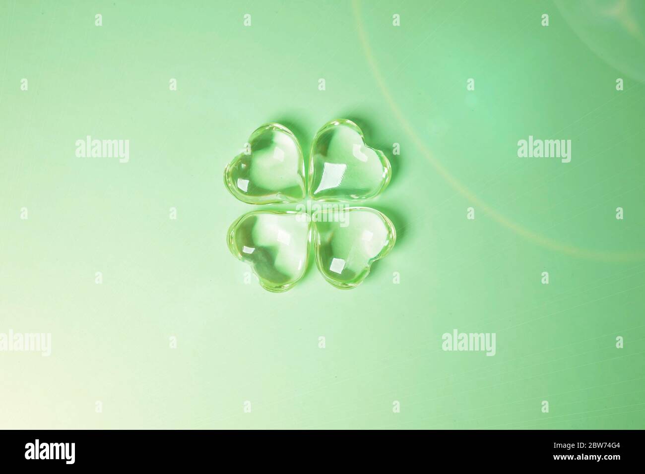 Imitation of a Lucky four leaf clover with four glass hearts on a green background for St. Patricks Day. Space for text, digital texture design concep Stock Photo