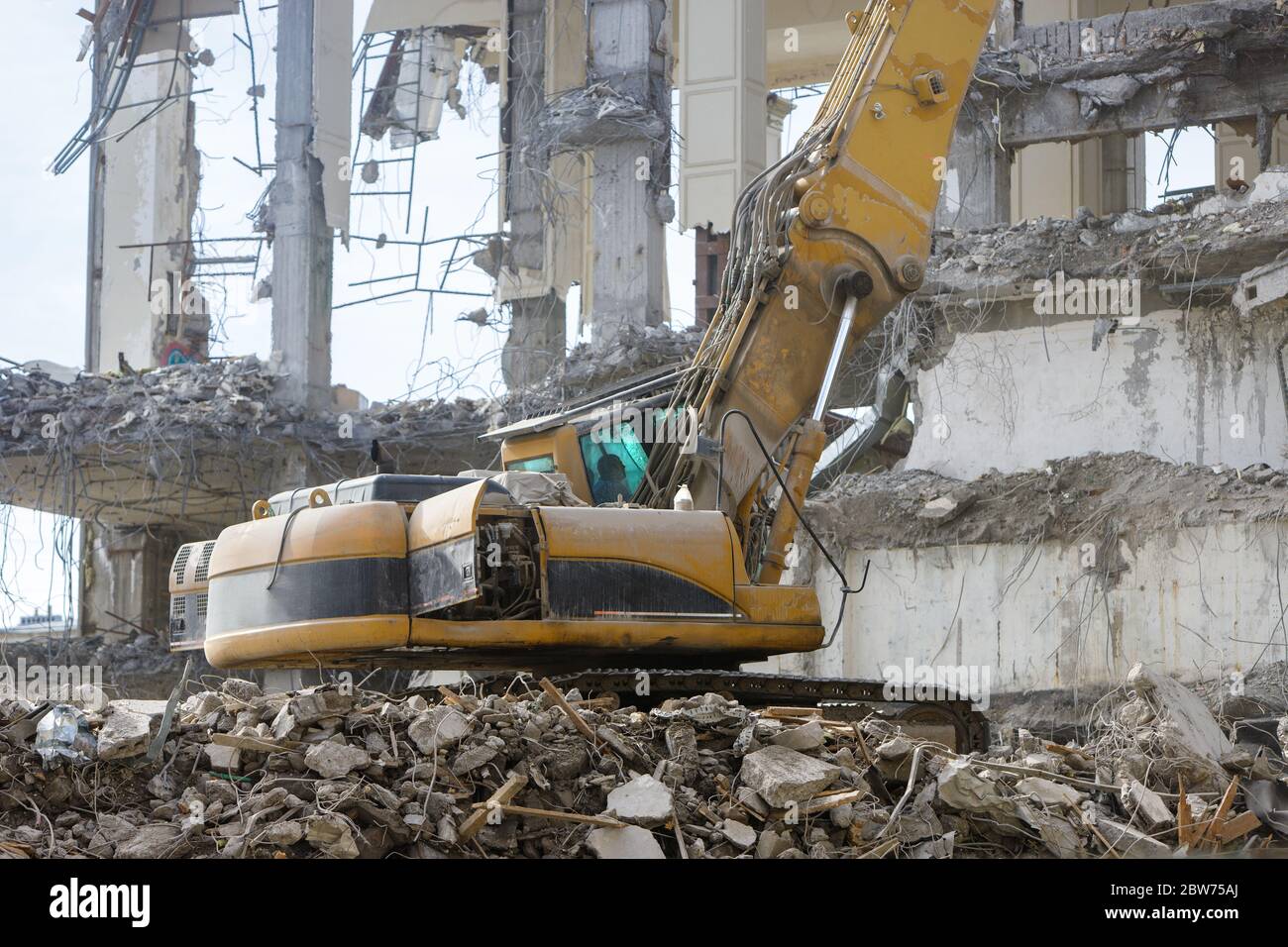 Closeup of special hydraulic excavator-destroyer during operation, ruins of a building on background. Ultra high demolition equipment Stock Photo