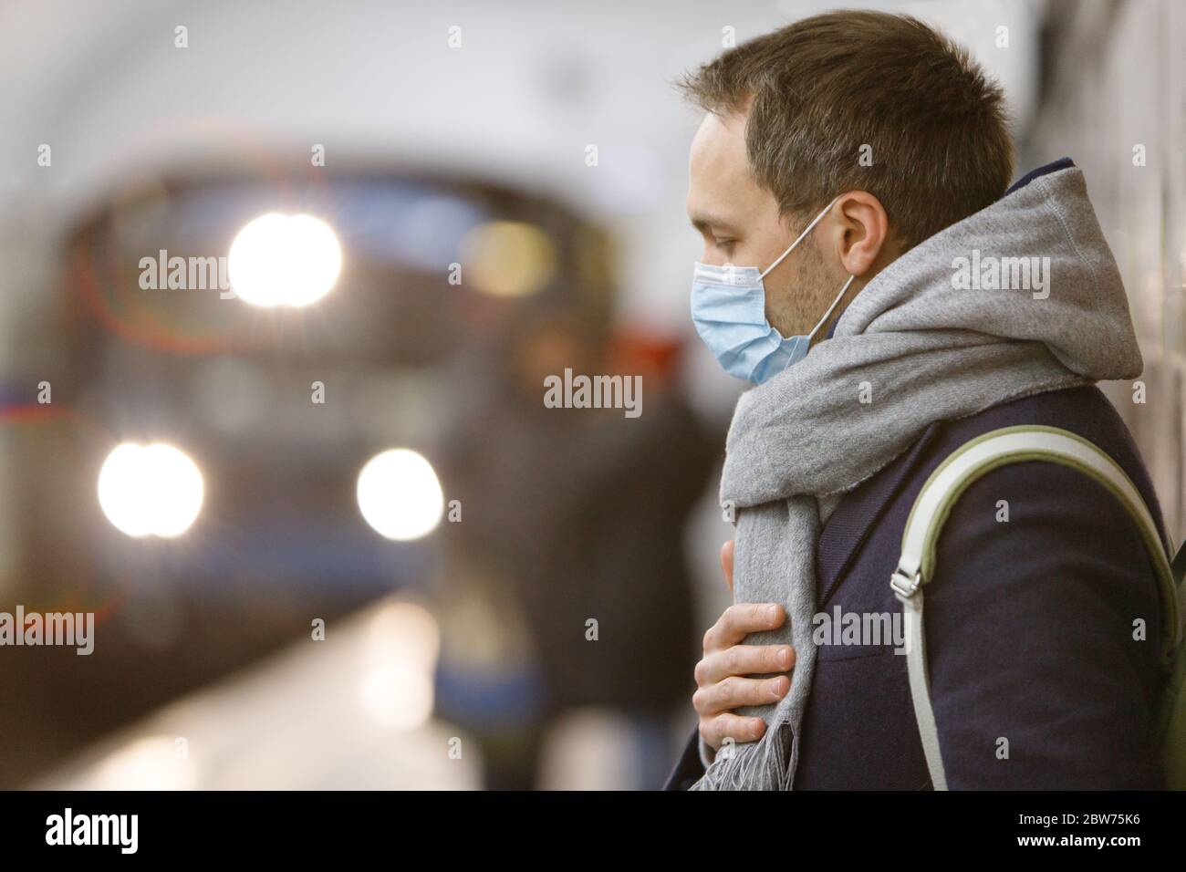Exhausted man feeling sick, wearing protective mask against transmissible infectious diseases and as protection against the flu in public transport/su Stock Photo