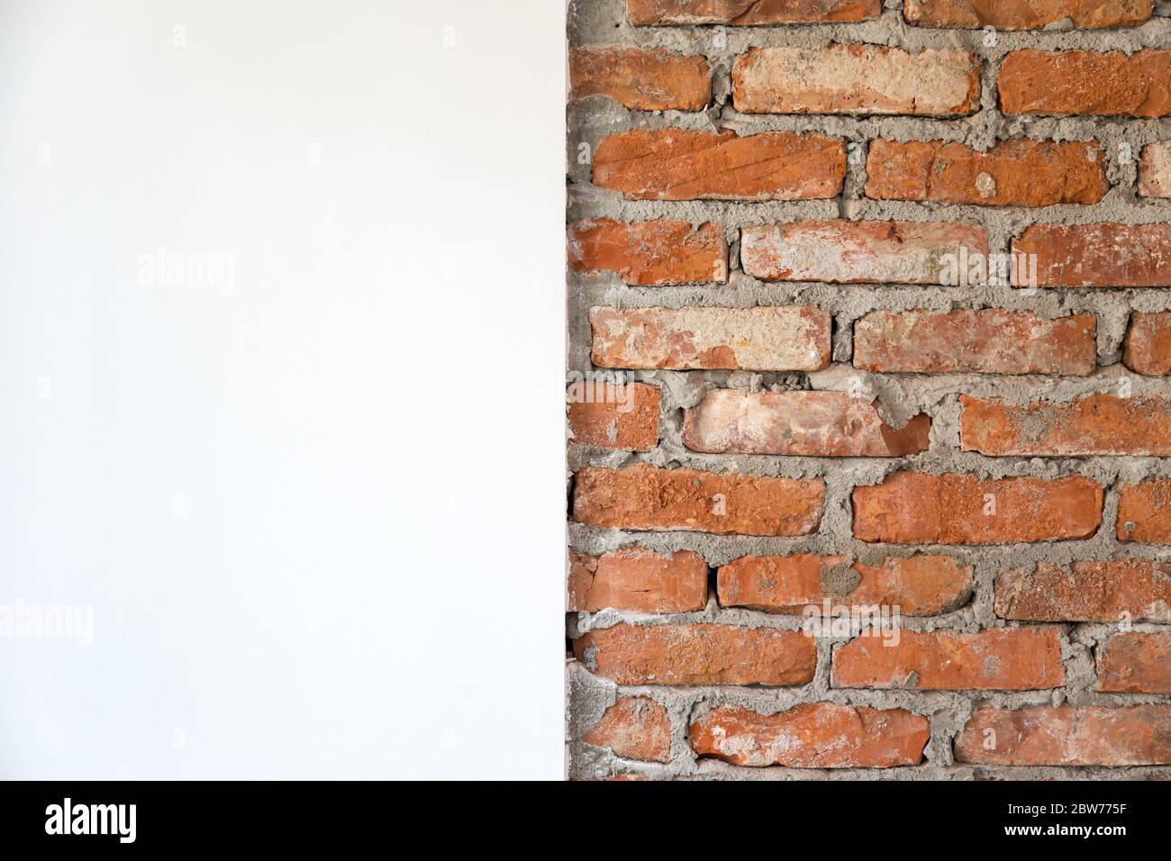 Wall with bricks and plaster and lime. Plastered and whitewashed wall next to a brick wall. Half wall with bricks and half with plaster and whitewashe Stock Photo