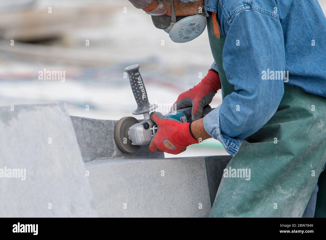 Saint John, New Brunswick, Canada - September 2, 2018: A sculptor uses power tools to shape to carve stone. Stock Photo