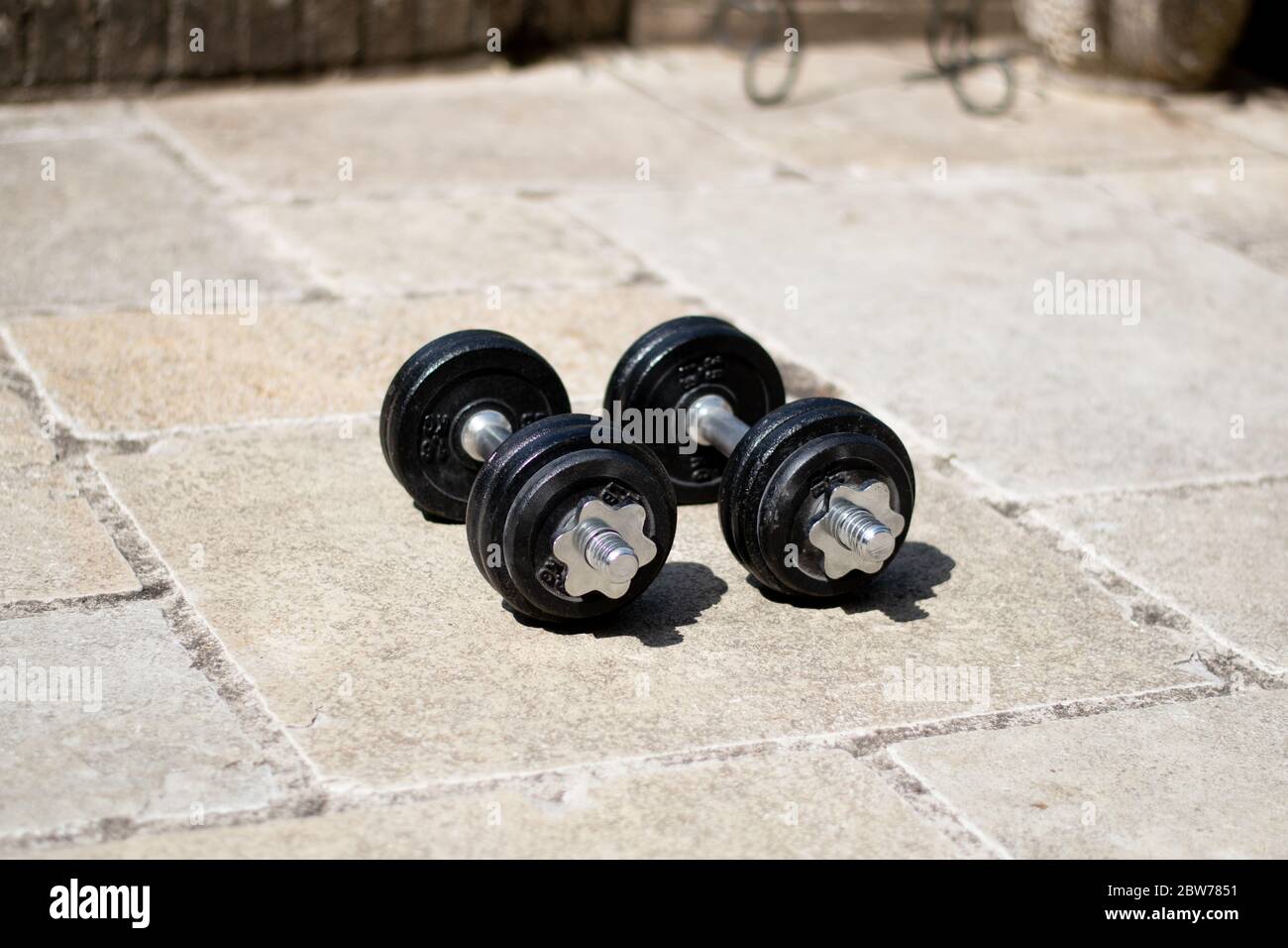 A set of dumbbell weights in a natural garden gym during lockdown. Stock Photo