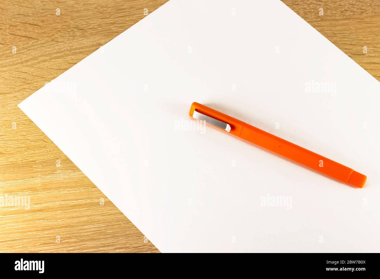 Blank sheet of paper and pen on bright wooden office desk. Ballpoint ...