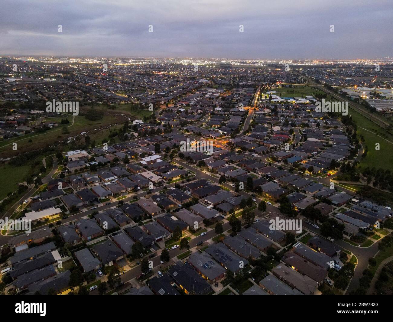 Aerial view of new homes built in new suburbs urban sprawl government rebates in evening with parkland and city lights Melbourne Victoria Australia Stock Photo