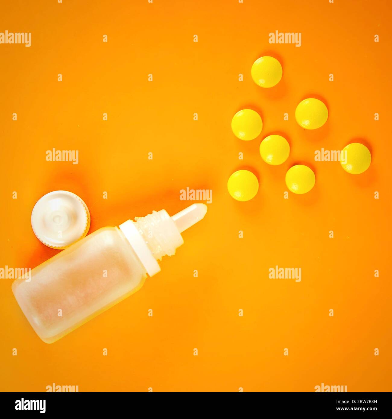 White plastic nasal spray with tablets on orange background sinusitis
