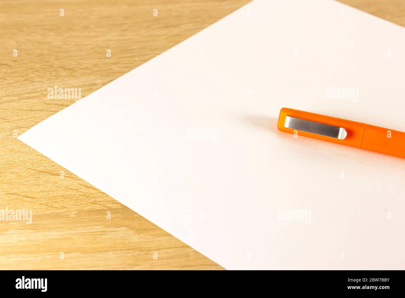 Blank sheet of paper and pen on bright wooden office desk. Ballpoint ...