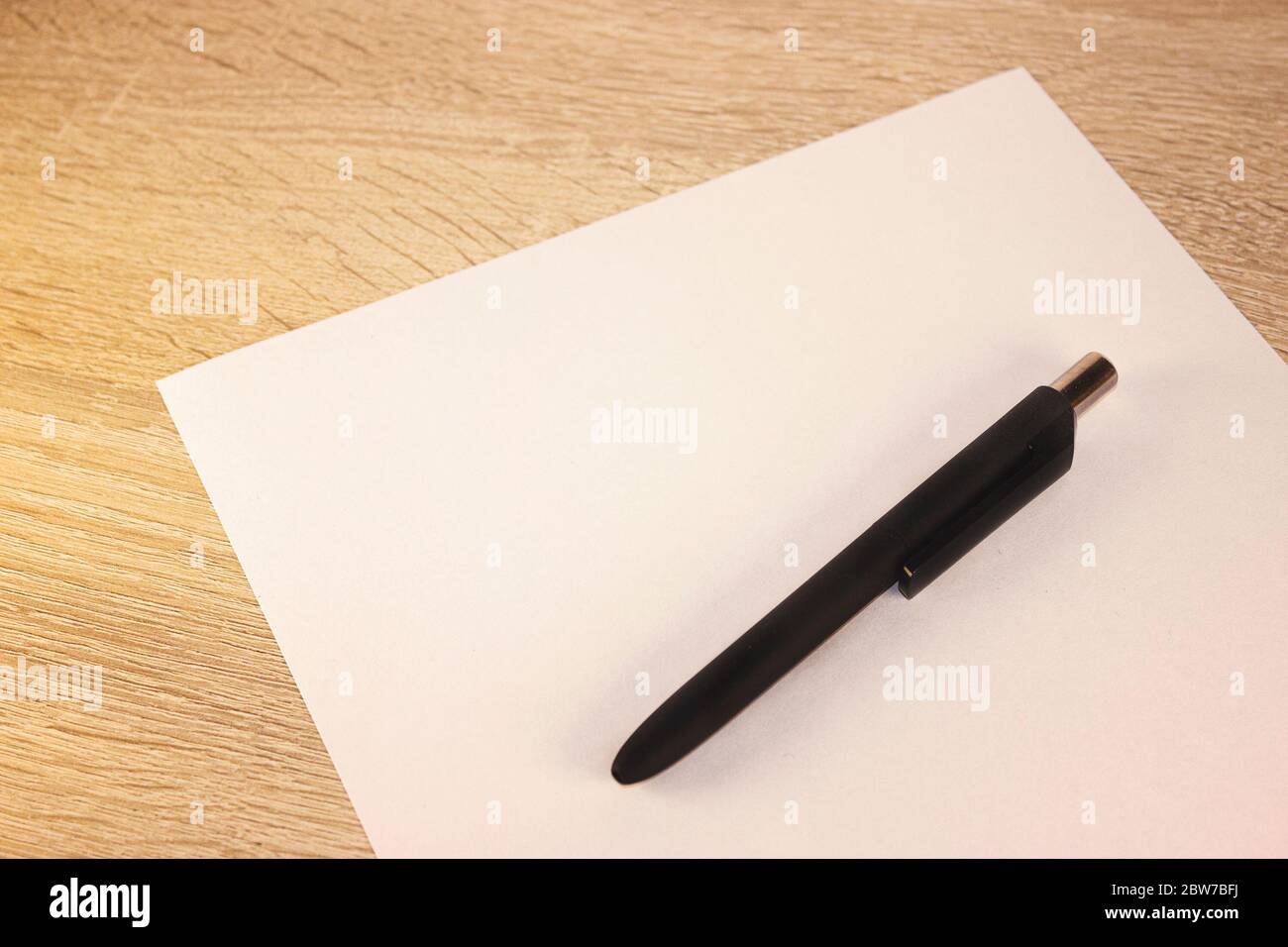 Blank sheet of paper and pen on bright wooden office desk. Ballpoint ...