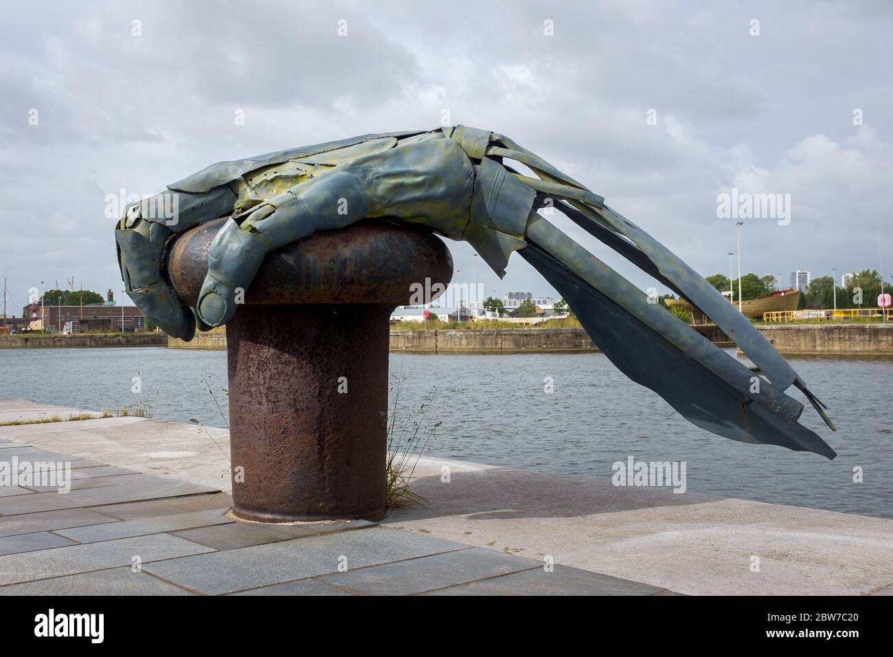 Old metal harbor bollard with the artwork 'The resurrection of Antigoon”, located next to the  Port House of Antwerp Stock Photo