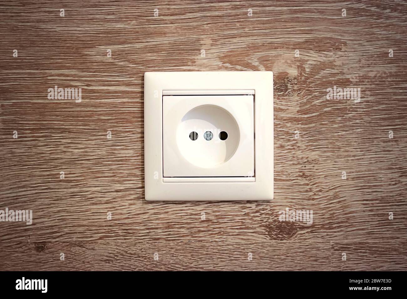 White european electrical outlet on a wood wall background. Concept electricity and minimalism. Stock Photo